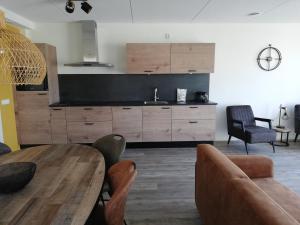 a kitchen with wooden cabinets and a table and chairs at Paardenstal in Hollum