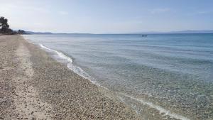 a beach with rocks and water and a boat in the distance at Villa Christina Sea Side in Hanioti