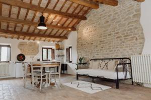 uma sala de estar com uma parede de pedra e uma mesa e cadeiras em Agriturismo Qui Voglio em Monte Roberto