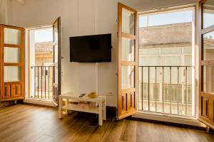 ein Wohnzimmer mit einem Flachbild-TV und 2 Fenstern in der Unterkunft Increíble Apto 3º San Miguel CentroCatedral+Parking+Wifi in Granada
