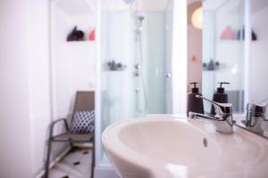 een witte badkamer met een wastafel en een douche bij Charmant Studio au coeur de Jaurès in Belfort