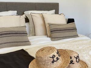 una cama con sombrero de paja y almohadas en Le Clos de la Chèvre Sud, en La Cadière-dʼAzur