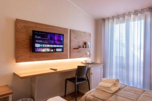 um quarto com uma secretária e uma televisão na parede em Hotel Palazzuolo em San Quirico dʼOrcia