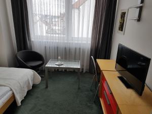 a room with a bed, chair, desk and television at Hotel Central in Pilsen