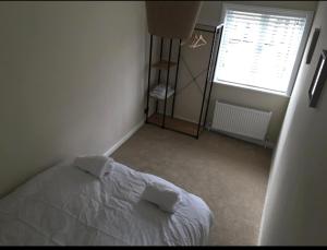 1 dormitorio con cama blanca y ventana en A quaint Wymondham cottage, en Norwich