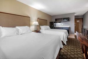 a hotel room with two beds with white sheets at Suburban Studios Lafayette in Lafayette