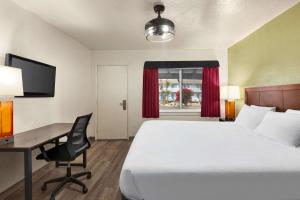 a hotel room with a bed and a desk with a computer at Baymont by Wyndham Fort Bragg in Fort Bragg