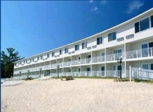 a large building on the beach next to the sand at Bridge Vista Beach Hotel and Convention Center in Mackinaw City