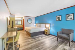 a hotel room with a bed and a desk and a chair at Days Inn by Wyndham Foley in Foley