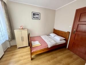 a small bedroom with a bed and a cabinet at Apartament Bursztyn, Willa Perla nad morzem in Gdańsk