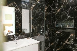 a black marble bathroom with a sink and a mirror at Athens Starlight Hotel in Athens