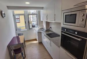 a kitchen with a sink and a microwave at Apartamentos Casa do Pan in Corme-Puerto