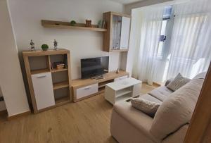a living room with a couch and a flat screen tv at Apartamentos Casa do Pan in Corme-Puerto