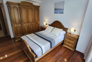 a bedroom with a bed and a wooden dresser at Apartamentos Casa do Pan in Corme-Puerto