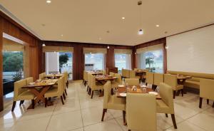 un ristorante con tavoli e sedie in legno e finestre di Hotel Fortune a Rāmeswaram