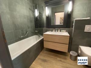 アーク 1950にあるStylish ski-in ski-out 3 bed apartment, Arc 1950の浴槽と洗面台とバスタブを備えたバスルーム