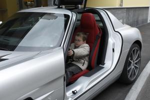 Un niño pequeño sentado en el asiento del conductor de un coche en Holiday Hotel YACHTSPORT RESORT Lago Maggiore, en Brissago