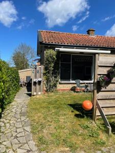 una pequeña casa con una bola de naranja en el patio en De Cel, en Nes
