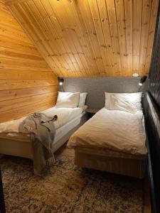 two beds in a room with a wooden ceiling at Villa Kyyhkynen in Rovaniemi