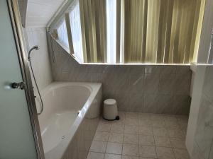 een kleine badkamer met een bad en een raam bij Stal Nieuwland in Vierpolders