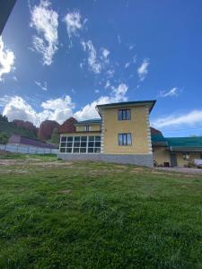 a building with a grass field in front of it at Emir in Dzhetyoguz