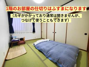 a room with a bed in a room with writing on the wall at Tetsu no YA Guesthouse for Railfans in Fuefuki