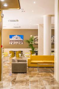 um átrio com sofás e mesas amarelos em Mercure Hotel President Lecce em Lecce