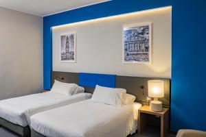 Dos camas en una habitación de hotel con paredes azules. en Mercure Hotel President Lecce, en Lecce