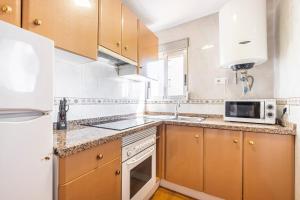 a kitchen with wooden cabinets and a white refrigerator at Los Ranchos 11 Apartment Levante Beach in Benidorm