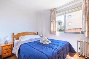a bedroom with a bed with a blue blanket and a window at Los Ranchos 11 Apartment Levante Beach in Benidorm