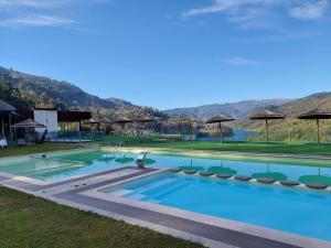 a large swimming pool with chairs and umbrellas at Dobau casas in Vieira do Minho