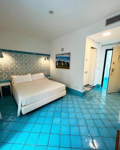 a bedroom with a bed and a blue tiled floor at Ganimede Hotel in Sperlonga