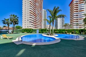 uma grande piscina com palmeiras e edifícios em Apartamentos Ambar Beach (1-8º-B) em Calpe