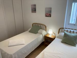 two beds in a small room with a lamp on a table at Beachfront and Renovated Apartment in Cullera