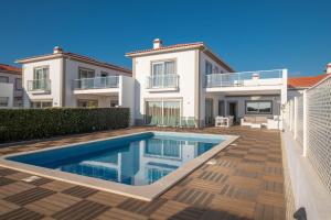 a villa with a swimming pool in front of a house at Vila do Golfe Villa in Casal da Lagoa Seca