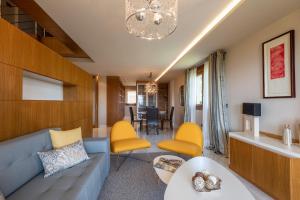 MA Maisons & Apartments Vista Alegre في Paxarinas: غرفة معيشة مع أريكة زرقاء وكراسي صفراء