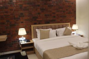 a bedroom with two beds and a brick wall at Hotel Royal Palm Dehradun in Dehradun