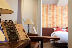 ein Hotelzimmer mit einem Bett und einem Tisch mit Büchern in der Unterkunft BOOK HOTEL 神保町 in Tokio