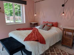 een slaapkamer met een groot bed met rode kussens bij La Pastorale in Manhay
