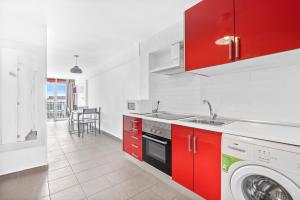 una cucina con armadi rossi e una lavatrice di Carabelas I 10-6 a Benidorm