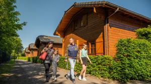 a family walking in front of a wooden house at EuroParcs De Achterhoek in Lochem