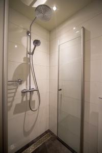 La salle de bains est pourvue d'une douche avec une porte en verre. dans l'établissement Unique Courtyard House with Sauna in Alkmaar city center, à Alkmaar