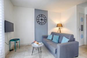 a living room with a couch and a clock on the wall at Le Grand Appart' proche commerces in Flers