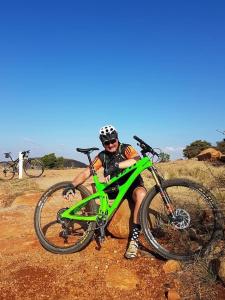 un hombre está sentado al lado de una bicicleta verde en Villa Paulina, en Langebaan