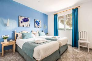 two beds in a room with blue walls at Villa Raquel Blanes in Cala en Forcat +23 photos