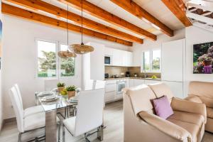a dining room and kitchen with white walls and wooden ceilings at Villa Raquel Blanes in Cala en Forcat