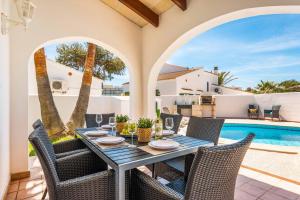 a patio with a table and chairs next to a pool at Villa Raquel Blanes in Cala en Forcat