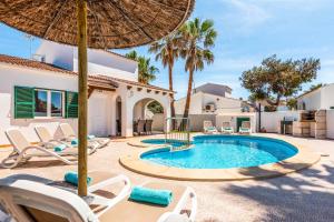 a villa with a swimming pool with chairs and an umbrella at Villa Raquel Blanes in Cala en Forcat