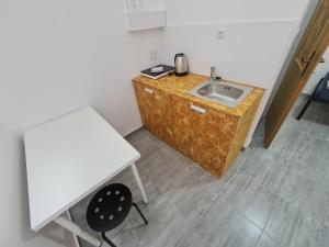 eine Küche mit einem Waschbecken, einem Tisch und einem Stuhl in der Unterkunft Budget Apartment LeLo Centar2 in Osijek