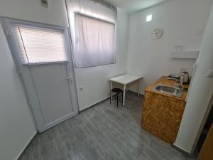 eine Küche mit einer Tür, einem Waschbecken und einem Tisch in der Unterkunft Budget Apartment LeLo Centar2 in Osijek